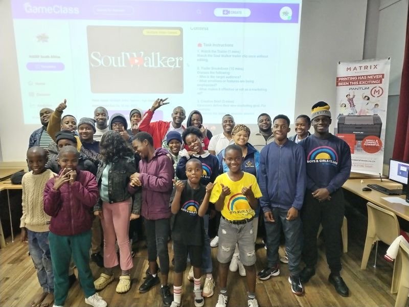 Students in Africa standing in front of a projector screen that has video game education platform GameClass on it